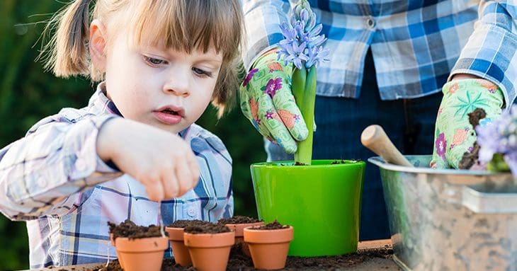 Child planting seeds in small pot